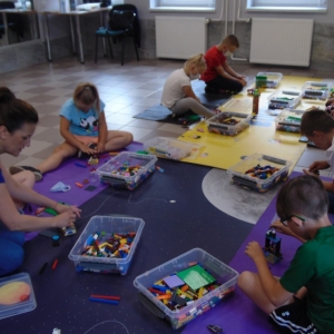 Uczestnicy warsztatów budujący modele z klocków Lego.